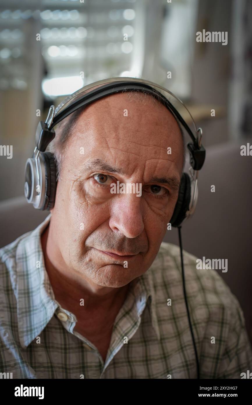 Germania. 24 agosto 2024. Uomo con cuffie ascolta musica o audiolibri sul divano Foto Stock