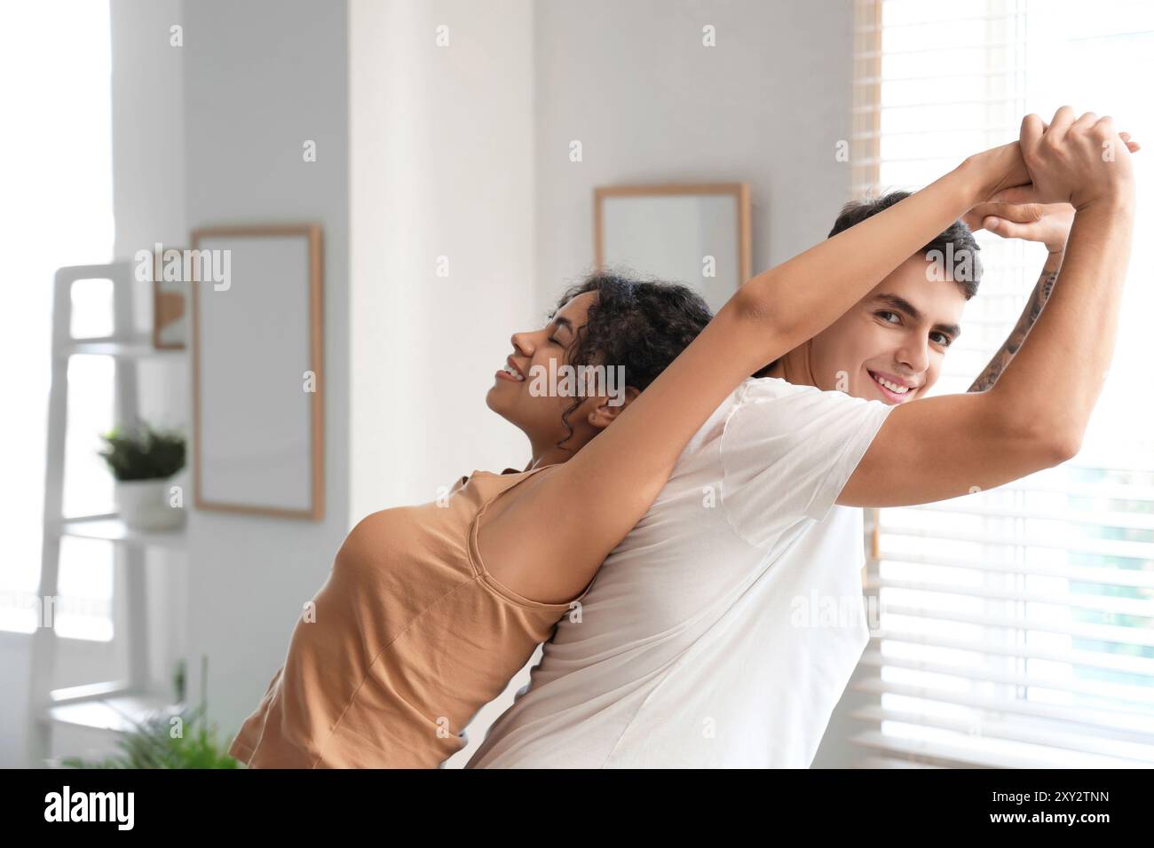 Giovane coppia che pratica yoga insieme a casa Foto Stock