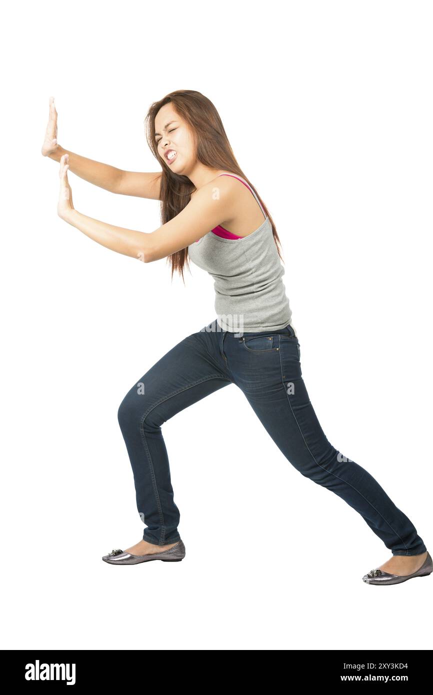 Donna asiatica in lotta in abiti casual, braccia estese, difesa, protezione, forzatura, peso corporeo inclinato, spinta e lotta contro immaginario (. Foto Stock