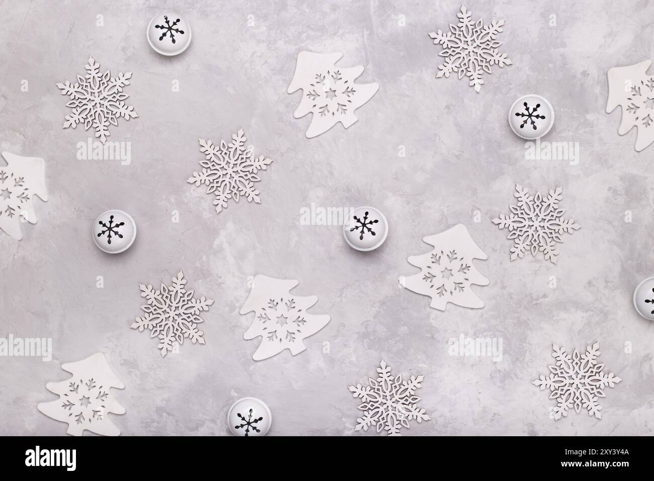 Modello natalizio piatto composto da fiocchi di neve campane e alberi su sfondo di pietra grigia. Concetto invernale Foto Stock