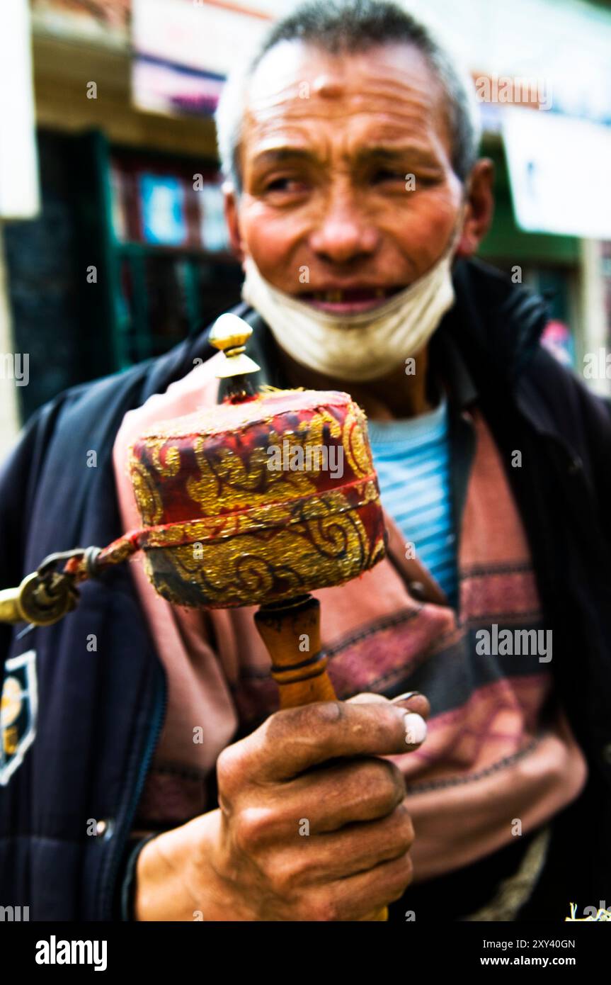 Un tibetano che gira la sua ruota di preghiera fuori da un monastero di Langmusi, provincia di Gansu, Cina. Foto Stock