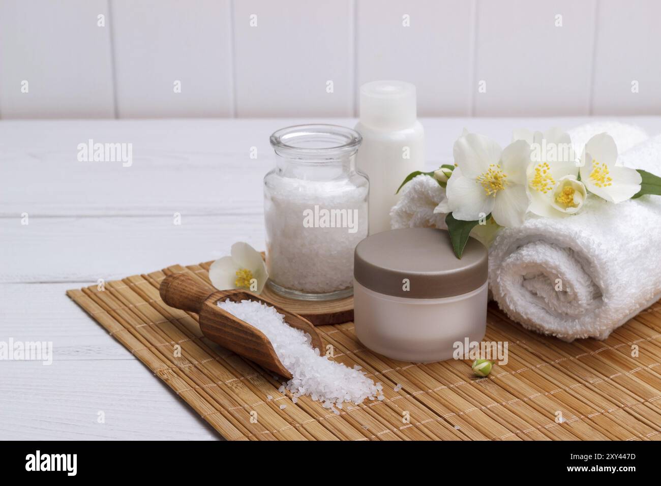 Ambiente spa e prodotti per la cura della salute, sapone aromatico jasmin, olio per il corpo, sale da bagno, latte, pietre per massaggi e asciugamani, su tavola di legno Foto Stock