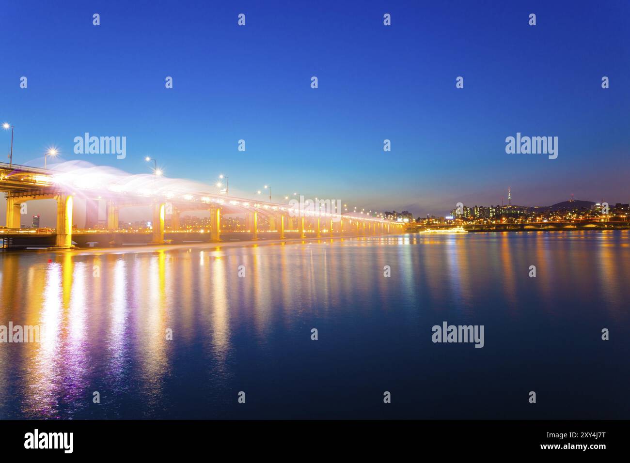 L'acqua spruzza dal lato del ponte Banpo nel fiume Han durante lo spettacolo di luci della Fontana dell'Arcobaleno al crepuscolo in una notte di cielo limpido a Seoul, Sout Foto Stock