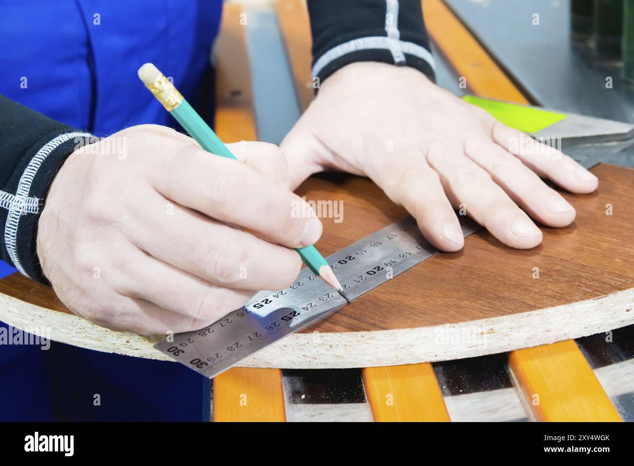 Il primo piano della mano del maestro del falegname è contrassegnato da un righello e da una matita vuota. Il concetto di produzione manuale di mobili Foto Stock