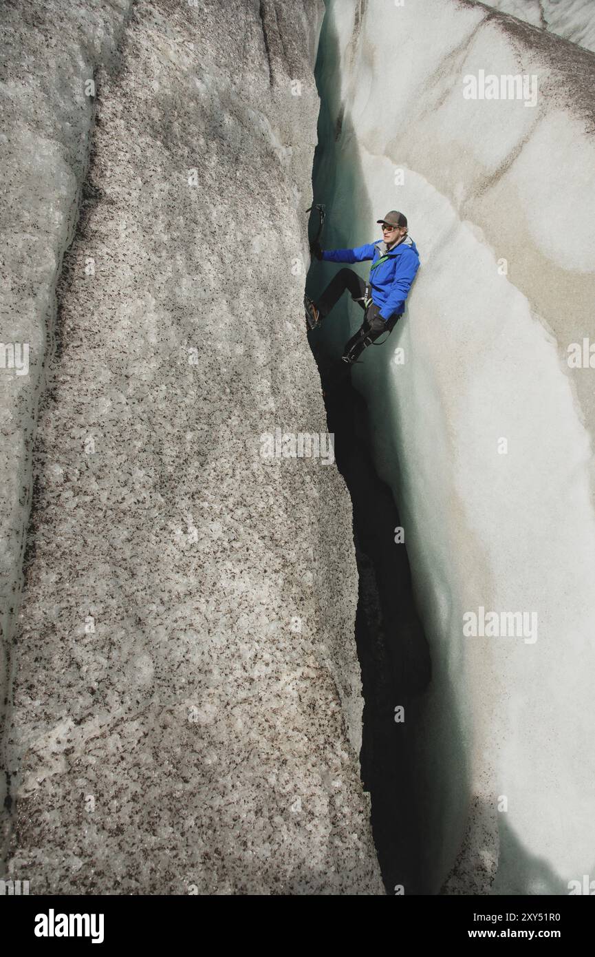 Un arrampicatore libero senza assicurazione con due assi di ghiaccio sale da una crepa nel ghiacciaio. Arrampicata libera senza corde Foto Stock