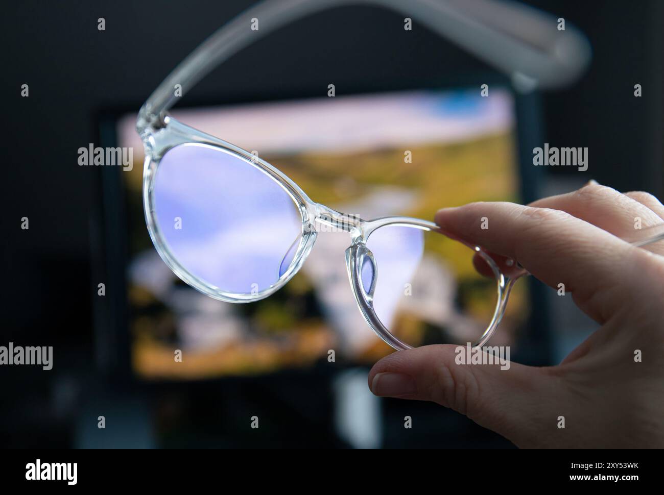 Messa a fuoco selettiva sugli occhiali e sullo schermo del computer con luce blu trasparente che si illuminano sullo sfondo a casa o in ufficio. Occhiali di luce blu. Foto Stock