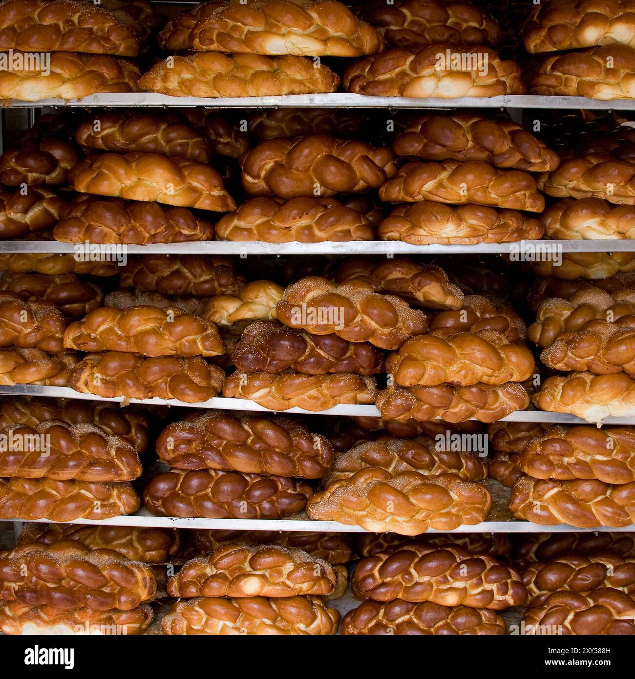 Pani di pane all'uovo appena intrecciato e cotto riposano su scaffali all'esterno di una panetteria in una strada di Gerusalemme alla vigilia del sabato ebraico. Foto Stock