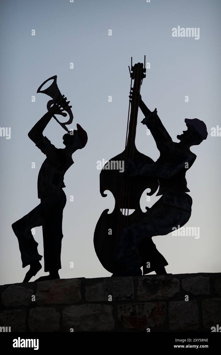 Silhouette metal ritagli di due musicisti che suonano un basso e una tromba verticali su un tetto nel nord di Israele. Foto Stock