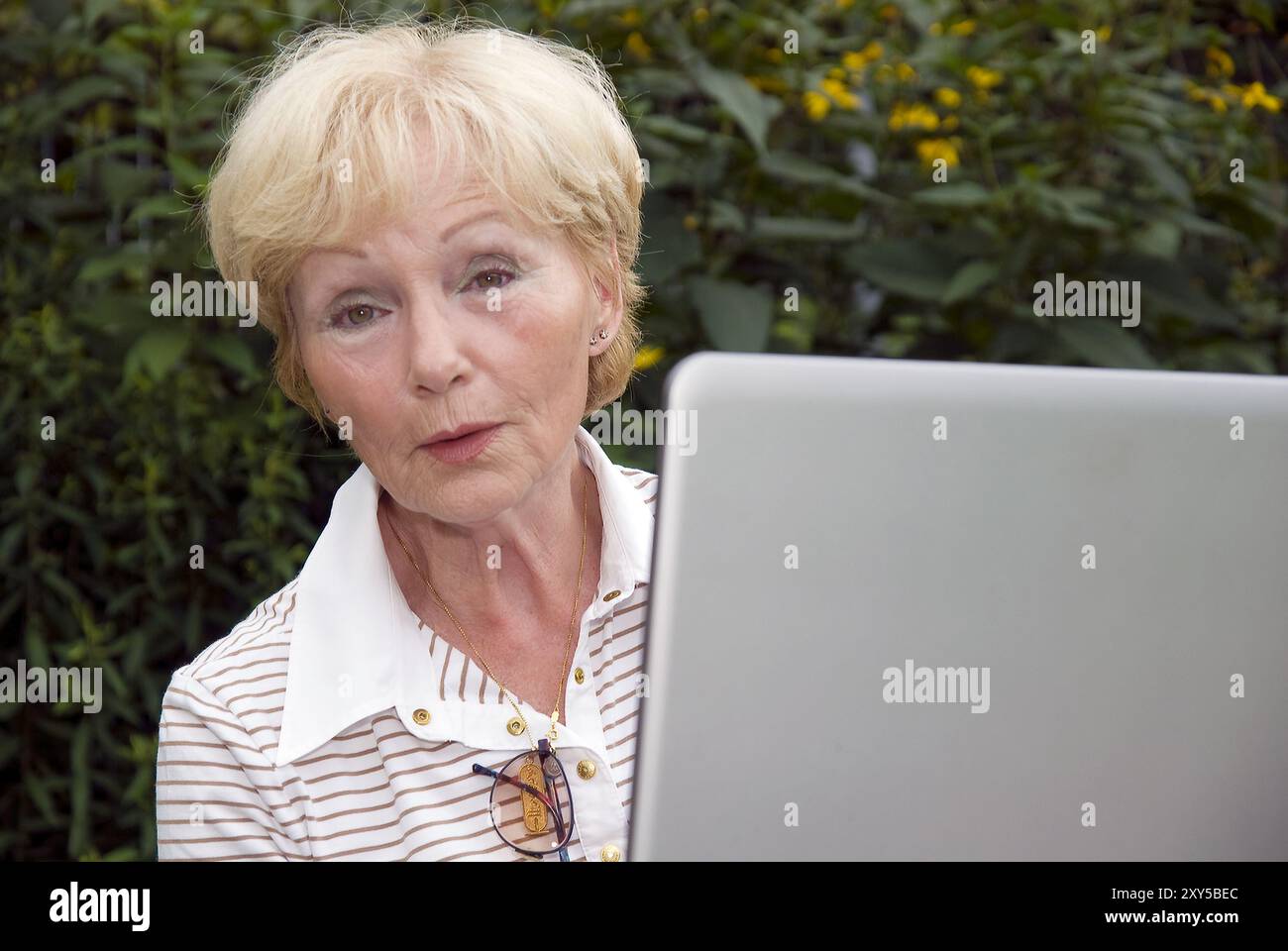 Anziano con un notebook in giardino Foto Stock