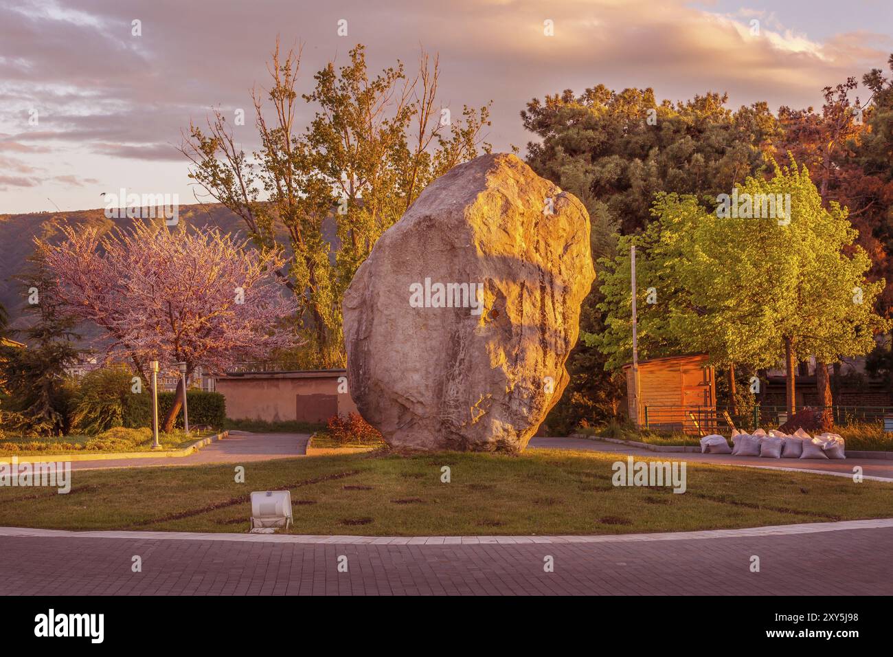 Grande pietra vicino alla chiesa della Santissima Trinità o alla cattedrale di Tsminda Sameba al tramonto a Tbilisi, Georgia, Asia Foto Stock