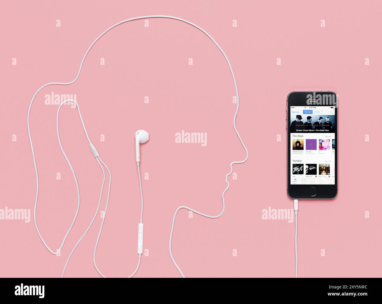 Profilo da donna realizzato con un cavo per cuffie collegato allo smartphone iPhone 5s con iTunes Music Store sul display. Concetto creativo su fondo rosa Foto Stock