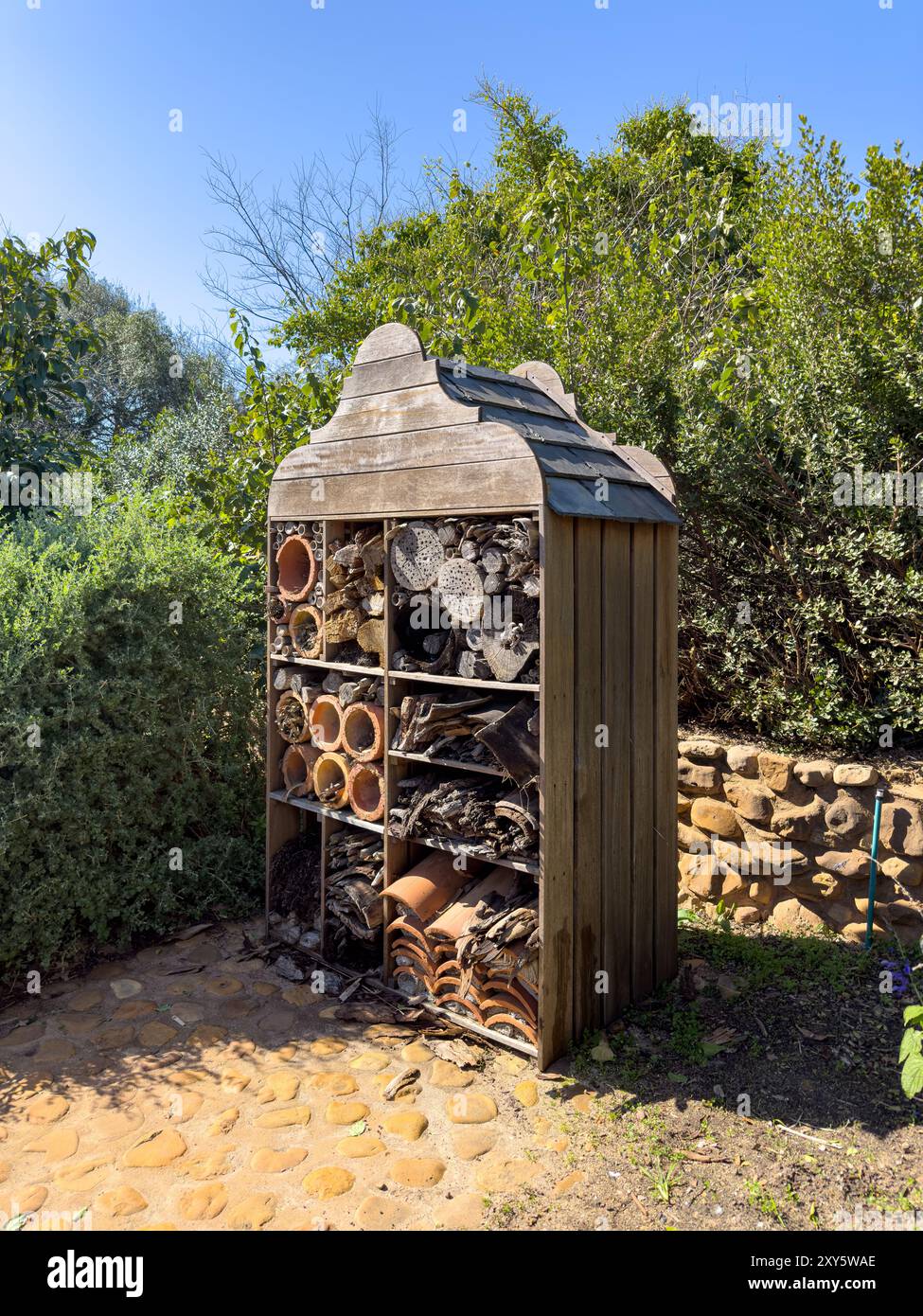 Un bug hotel in un giardino che fornisce rifugio e siti di nidificazione a insetti nativi, migratori e solitari Foto Stock
