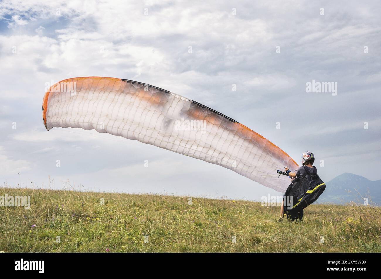 Il parapendio apre il suo paracadute prima di decollare dalla montagna nel Caucaso settentrionale. Riempimento dell'ala paracadute con aria prima del decollo Foto Stock