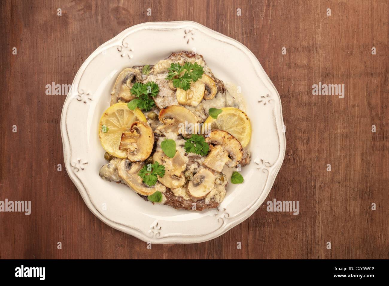 Foto aerea di scallopine di vitello, scallopini di vitello con salsa di funghi, limoni e prezzemolo, al buio su un sfondo rustico con un posto per tex Foto Stock