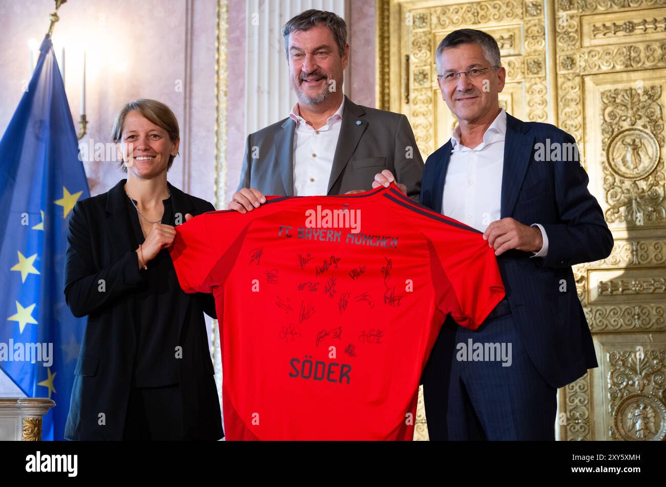 Monaco, Germania. 28 agosto 2024. Markus Söder (M, CSU), ministro presidente della Baviera, riceve le calciatrici del Bayern Monaco e gli viene presentata una maglia da Bianca Rech, direttore del Bayern Women, e Herbert Hainer, presidente del Bayern Monaco. Söder ha onorato i giocatori e la squadra di allenatori per aver vinto il Campionato tedesco 2023/24. Crediti: Sven Hoppe/dpa/Alamy Live News Foto Stock Monaco, Germania. 28 agosto 2024. Markus Söder (M, CSU), ministro presidente della Baviera, riceve le calciatrici del Bayern Monaco e gli viene presentata una maglia da Bianca Rech, direttore del Bayern Women, e Herbert Hainer, presidente del Bayern Monaco. Söder ha onorato i giocatori e la squadra di allenatori per aver vinto il Campionato tedesco 2023/24. Crediti: Sven Hoppe/dpa/Alamy Live News Foto Stock