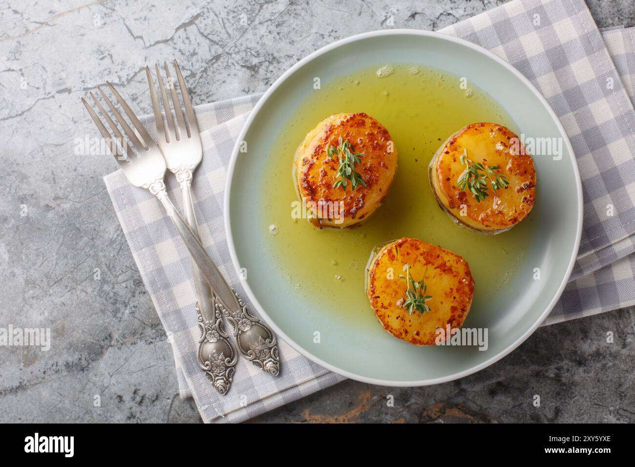 Le patate fondenti sono un piatto tradizionale francese in cui si cuocono le patate, quindi si brasano il burro, l'aglio, le erbe e il brodo in primo piano sul pla Foto Stock
