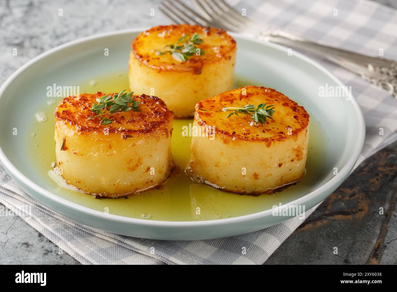 Le patate fondenti sono un piatto tradizionale francese in cui si cuocono le patate, quindi si brasano il burro, l'aglio, le erbe e il brodo in primo piano sul pla Foto Stock