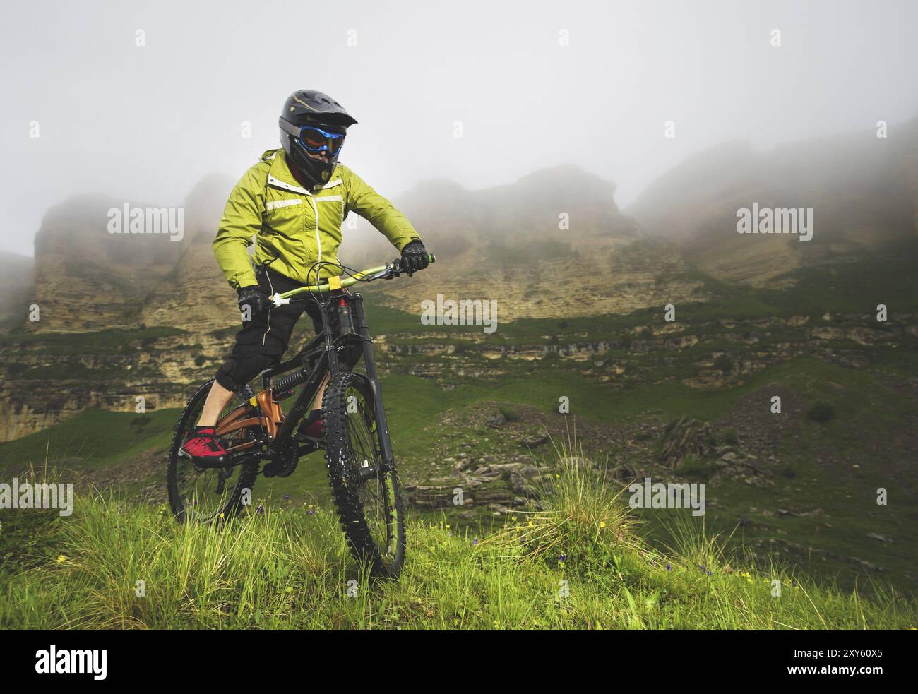 Un uomo in un casco di montagna che cavalcano una mountain bike gira intorno alla natura bella in tempo nuvoloso. Discesa Foto Stock