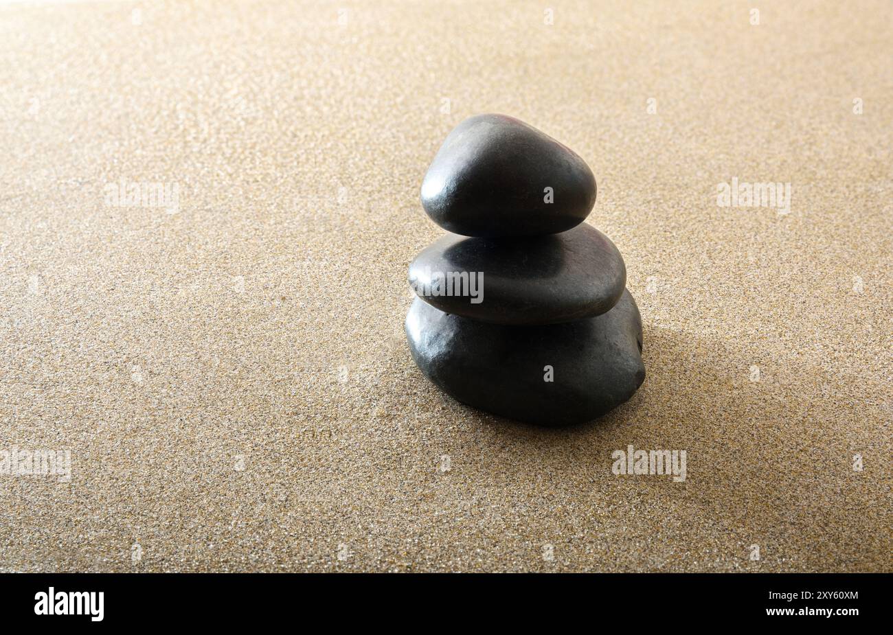 Mucchio di pietre nere sulla sabbia. Concetto di equilibrio e benessere. Concetto di equilibrio e salute. Foto Stock