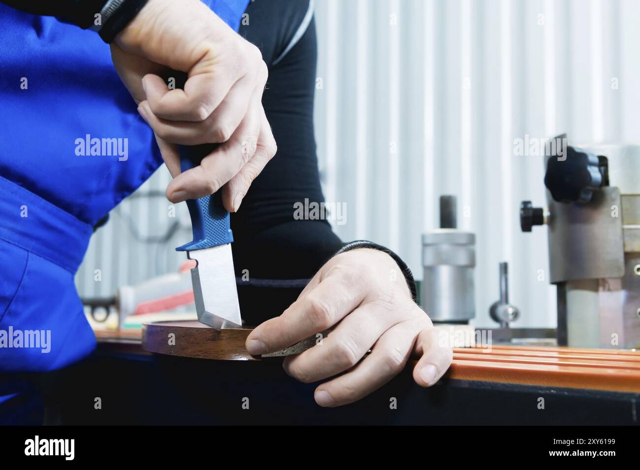 Un primo piano delle mani non ben curate del vero falegname maschile completa la finitura dei dettagli in truciolato dei mobili tagliando il bordo Foto Stock