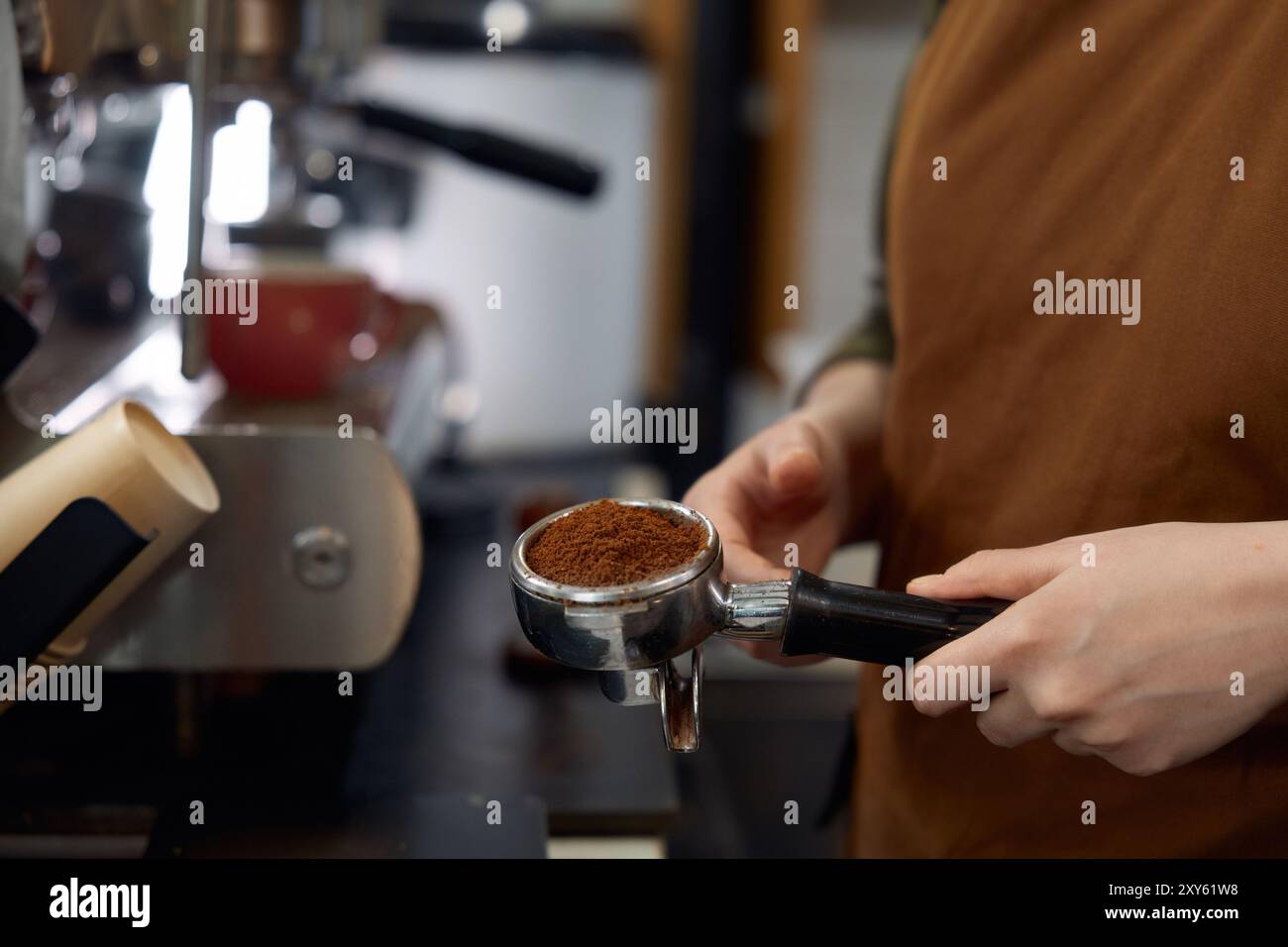 Barista che tiene in mano il portafiltro con chicchi macinati pronti per preparare un espresso classico Foto Stock