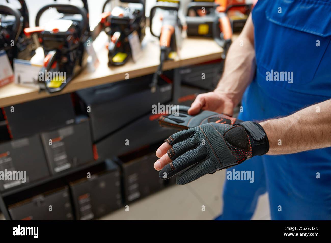 Il proprietario di un negozio di ferramenta indossa guanti da costruzione Foto Stock
