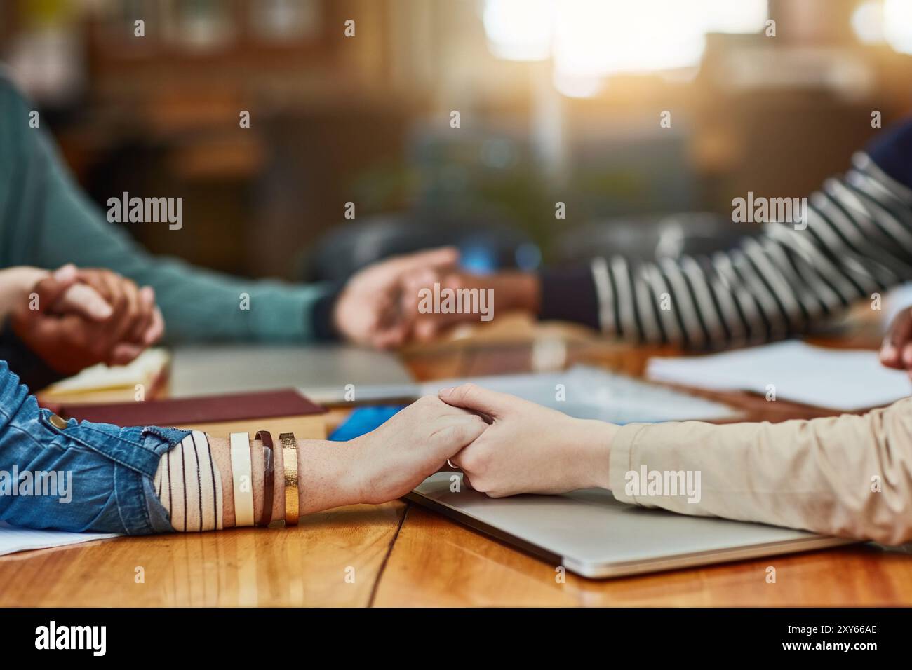 Le persone, la bibbia studiano o si tengono per mano a tavola per la preghiera, la gratitudine o il culto alla tecnologia. Gruppo religioso, gesto spirituale o incontro in biblioteca per Foto Stock