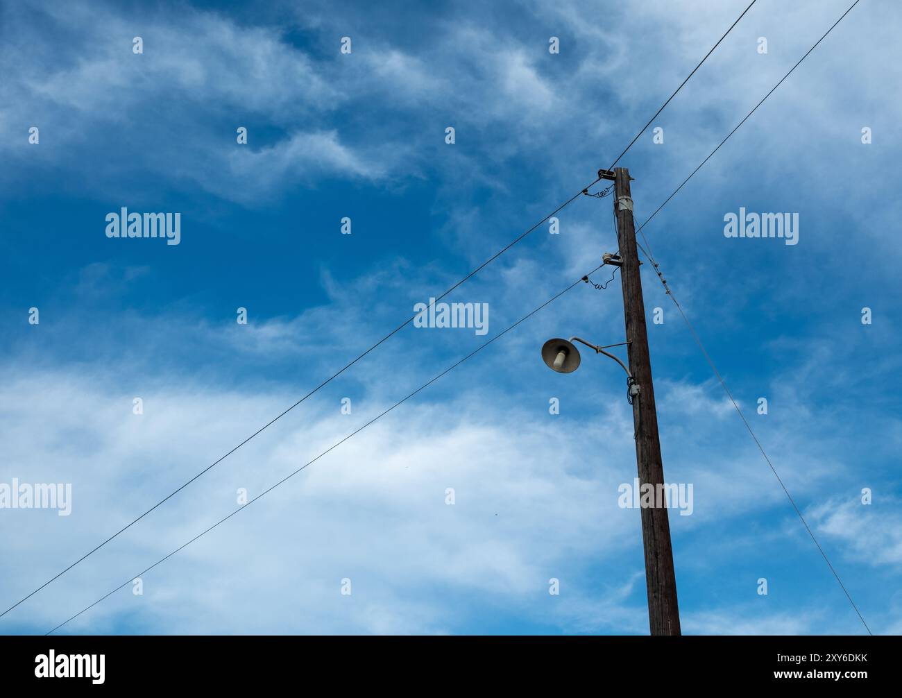 Illuminazione stradale retrò, lampadina vintage su asta elettrica in legno. Lampada a colonna in vecchio stile, sfondo blu nuvoloso del cielo, spazio di copia Foto Stock