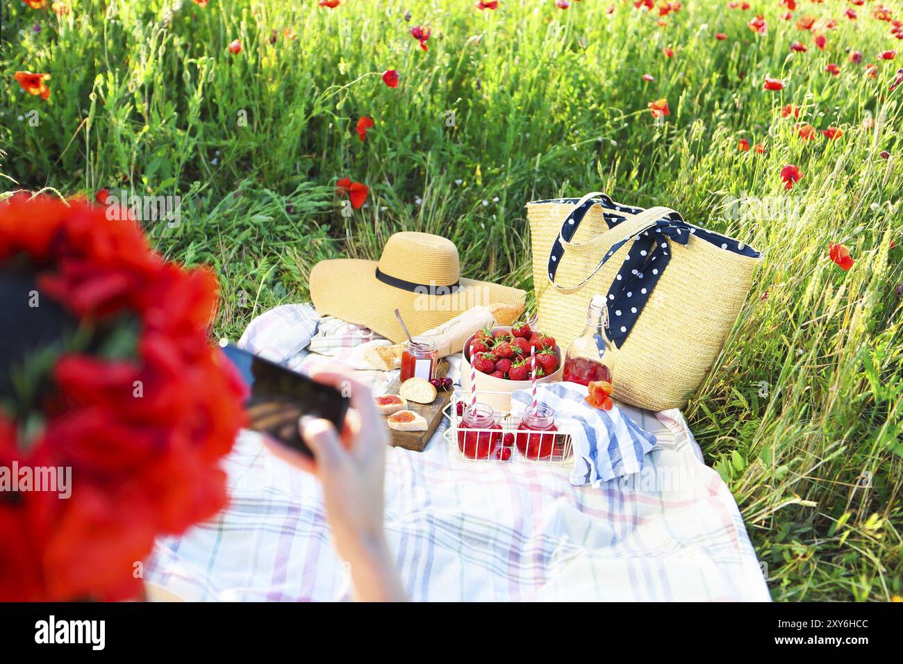 Cestello, panini, plaid e succo in un campo di papavero. Vintage sfondo di gara. Il romanticismo, amore, data la donna prendendo mobile photo per instagram Foto Stock