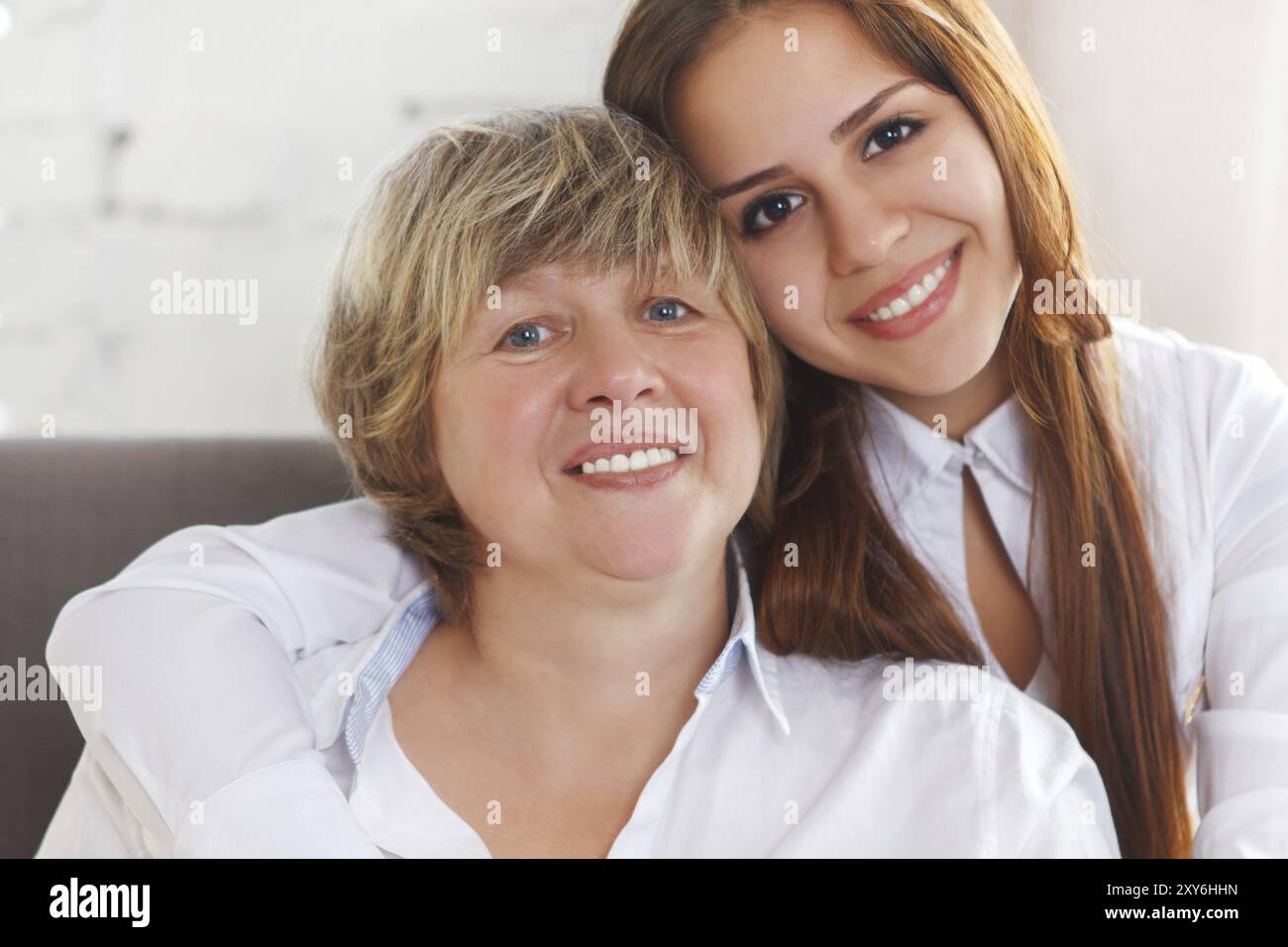 Ritratto di una nonna matura e di una nipote adolescente e di una nipote adolescente che si avvicinano e si abbracciano a casa per essere felici e gioiosi Foto Stock