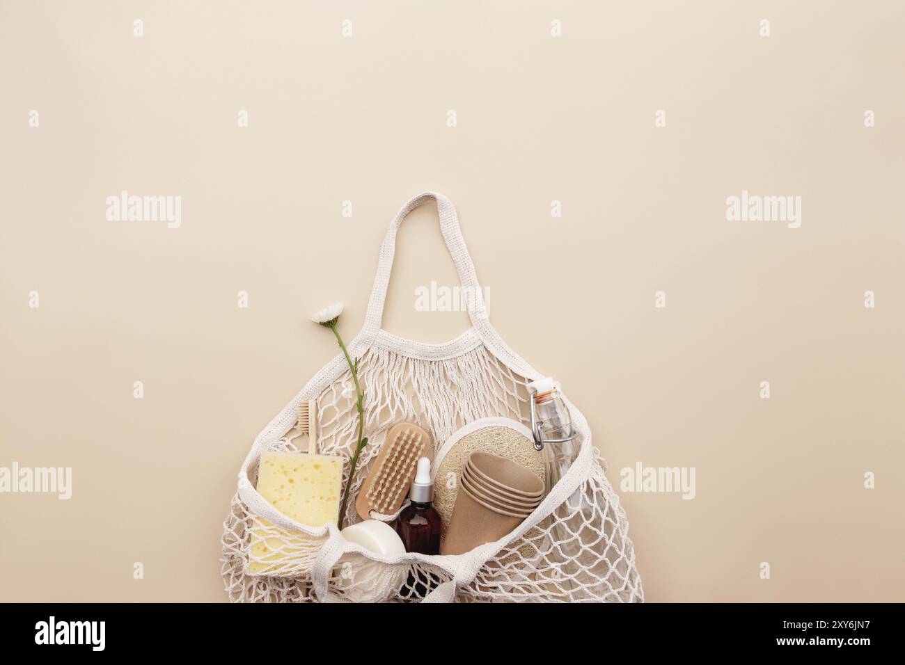 Eco friendly concetto estivo su sfondo beige con borsa eco shopping, fiori camomilla bianco, accessori da bagno, bottiglia di vetro d'acqua, sapone, dentifricio Foto Stock