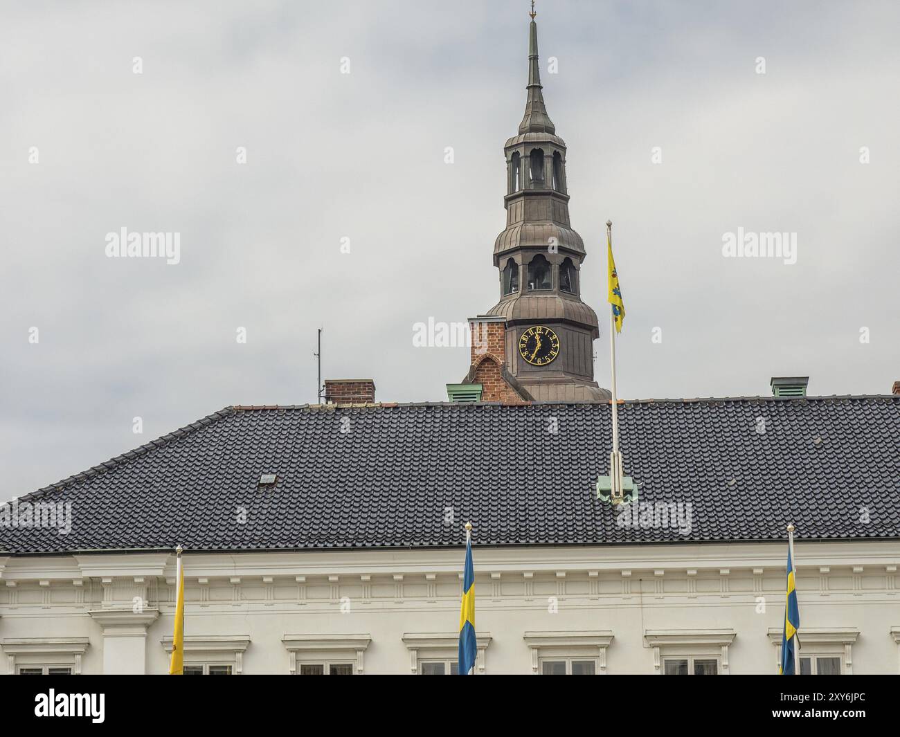 Edificio storico con orologio a torre e bandiere svedesi di fronte, svaneke, bornholm, Mar baltico, danimarca, scandinavia Foto Stock