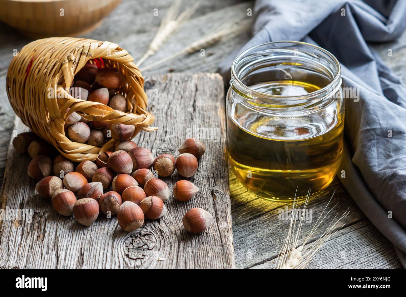 Olio di nocciole, filberto e olio da cucina in un bicchiere di vaso su sfondo di legno, mucchio o pila di nocciole, cibo salutare Foto Stock