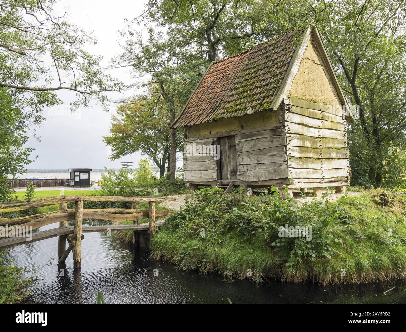 Piccola capanna in legno con un tetto coperto di muschio e un ponte in legno su un piccolo torrente, incastonato nella natura, Bad Zwischenahn, ammerland, germania Foto Stock Piccola capanna in legno con un tetto coperto di muschio e un ponte in legno su un piccolo torrente, incastonato nella natura, Bad Zwischenahn, ammerland, germania Foto Stock