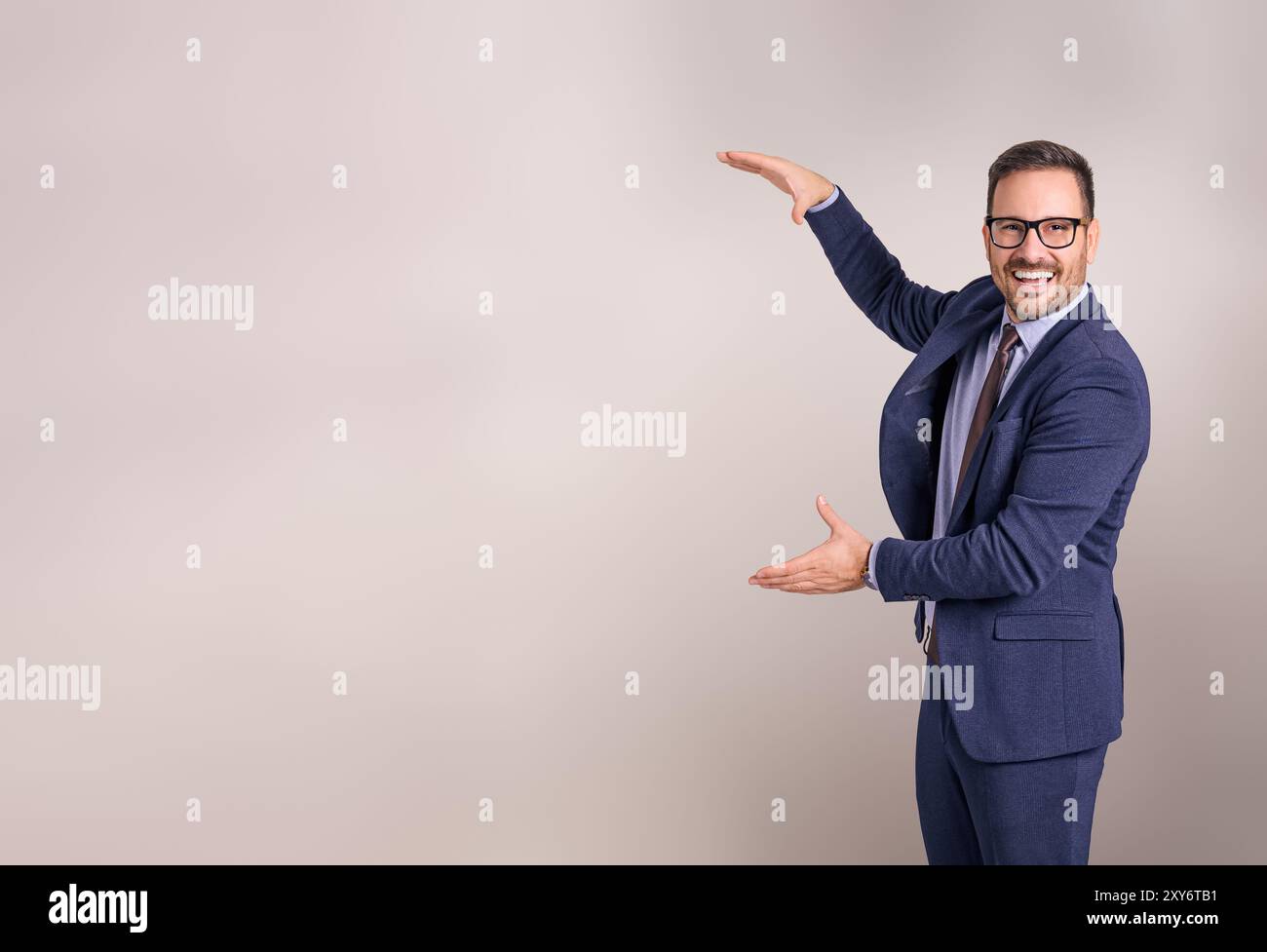 Ritratto di un giovane venditore sorridente che presenta e pubblicizza il nuovo prodotto su sfondo bianco Foto Stock