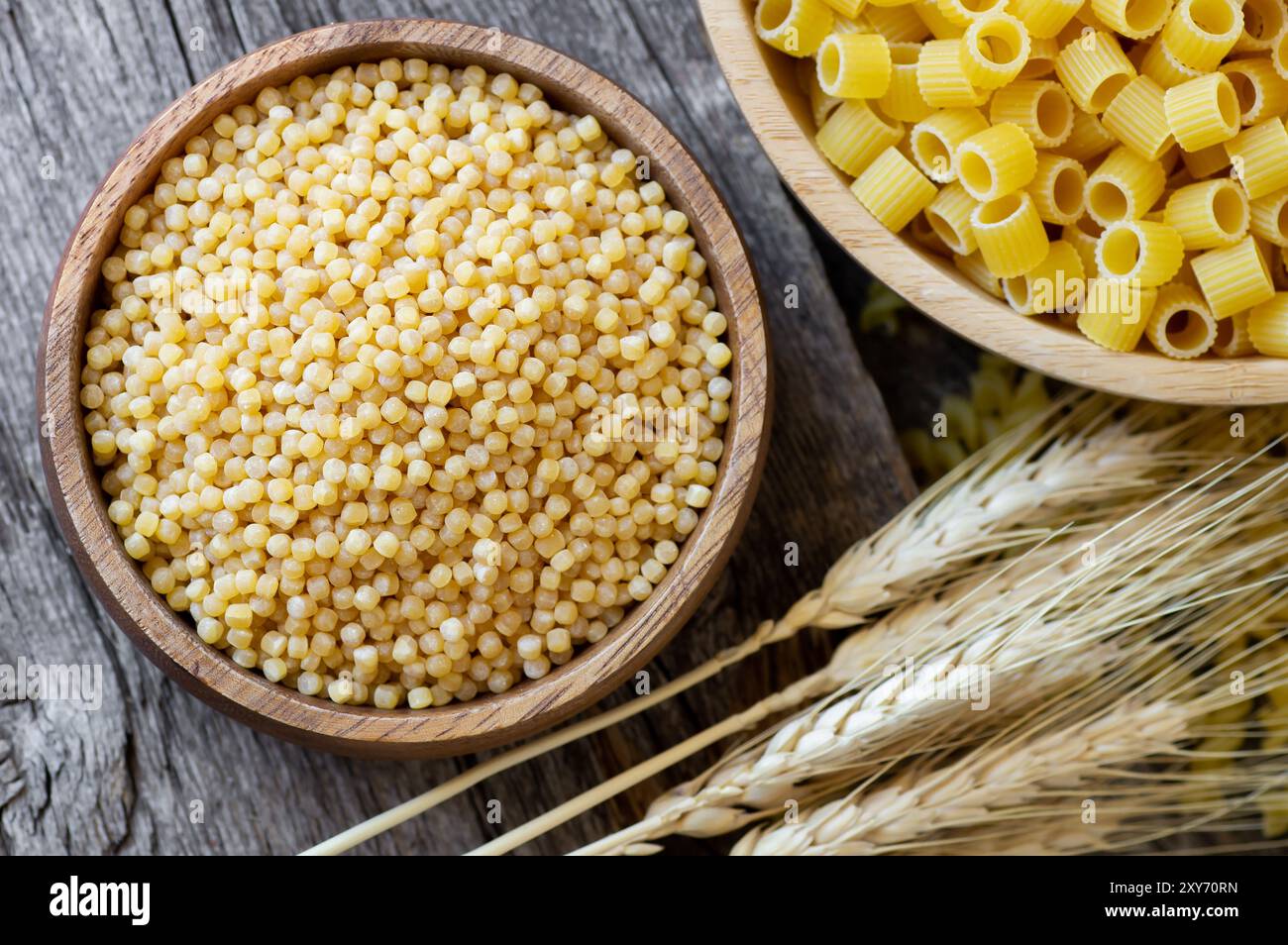 Couscous crudo in ciotola su sfondo di legno con affettati, concetto di cibo crudo Foto Stock