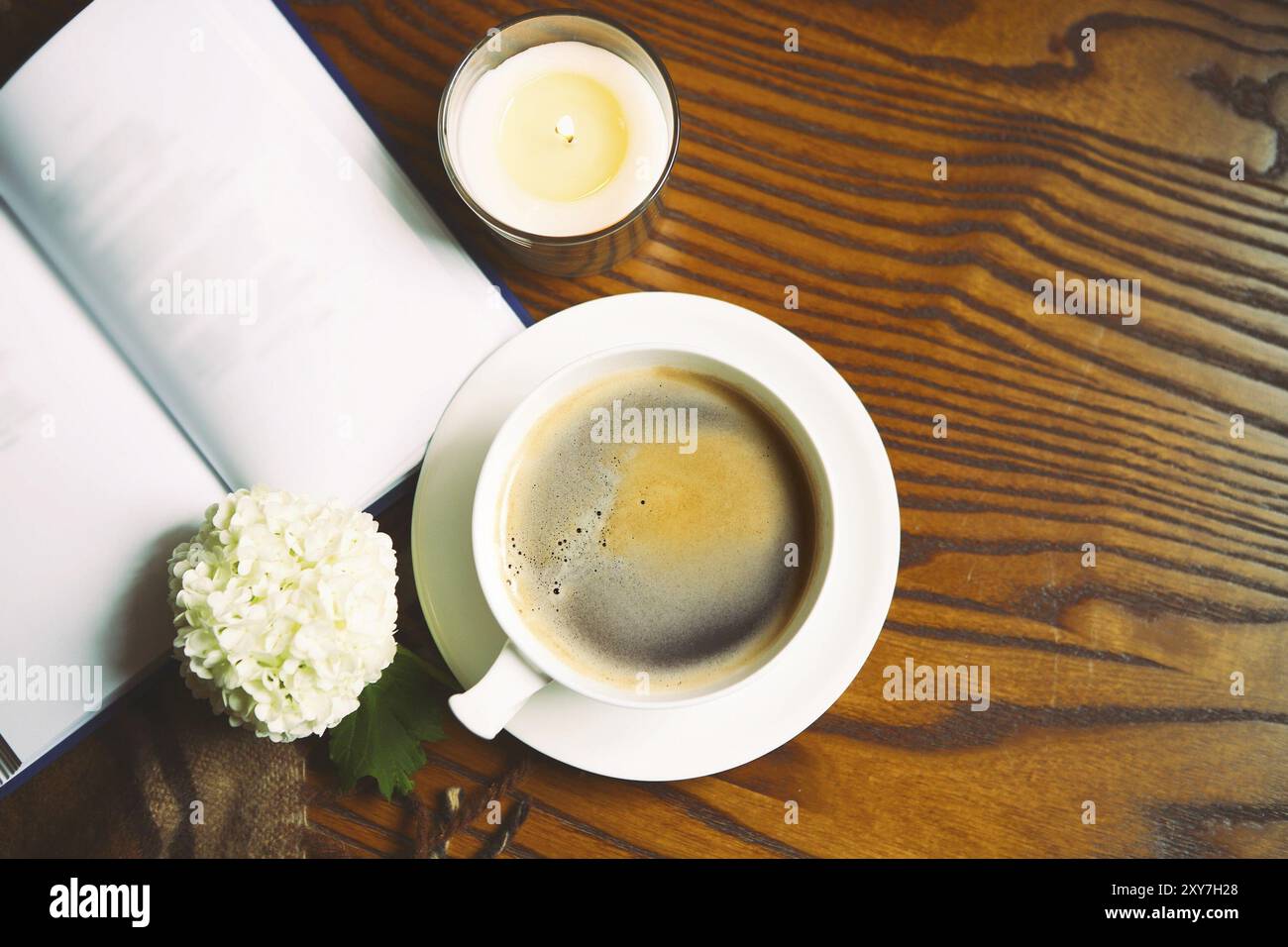 Caffè, libro, plaid e candela in casa. Cibo, hygge e concetto di comfort Foto Stock