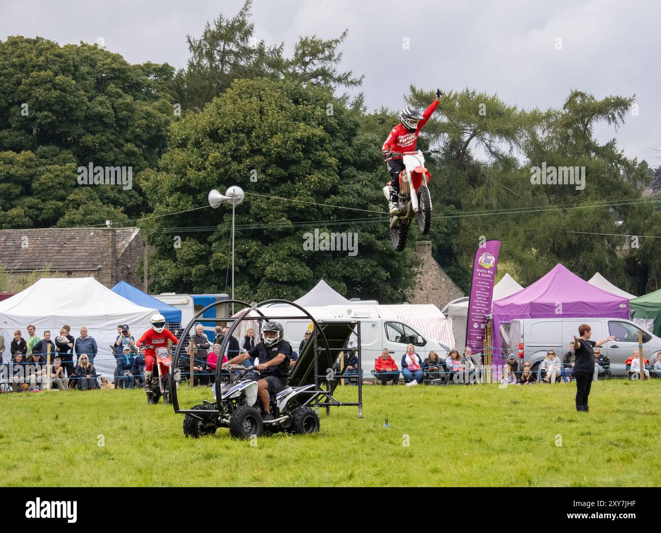 Uno stunt man su una bicicletta che va oltre un salto al Reeth Show di Swaledale, Yorkshire Dales, Regno Unito. Foto Stock