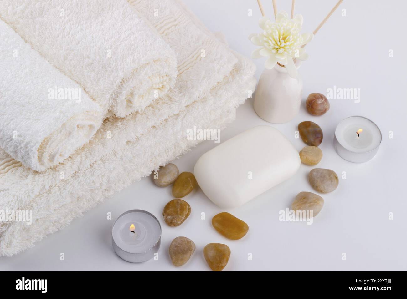 Spa e benessere sapone impostazione asciugamani bianchi fiori pietre aroma candele bastoni sfondo bianco Foto Stock