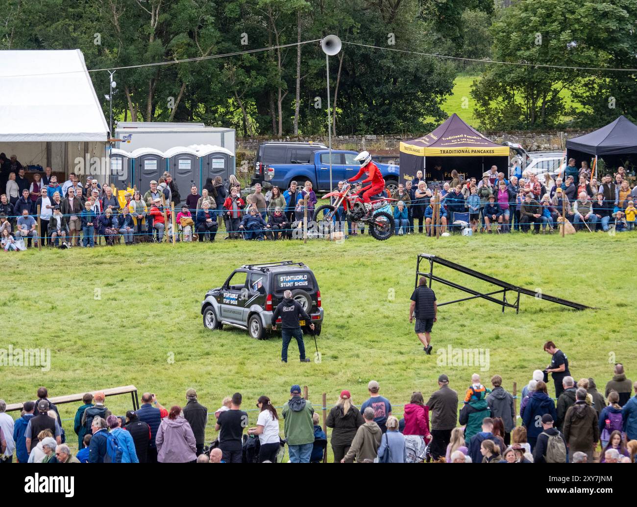 Uno stunt man su una bicicletta che va oltre un salto al Reeth Show di Swaledale, Yorkshire Dales, Regno Unito. Foto Stock