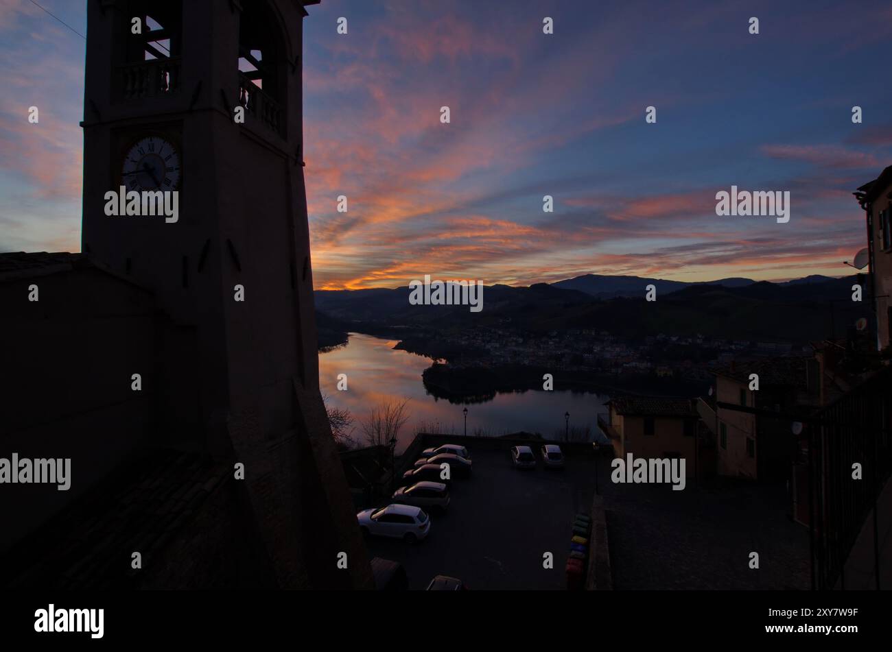 Panorama del lago di Mercatale, visto dalla piazza dell'orologio del paese di Sassocorvaro, contro un cielo scenografico al tramonto Foto Stock