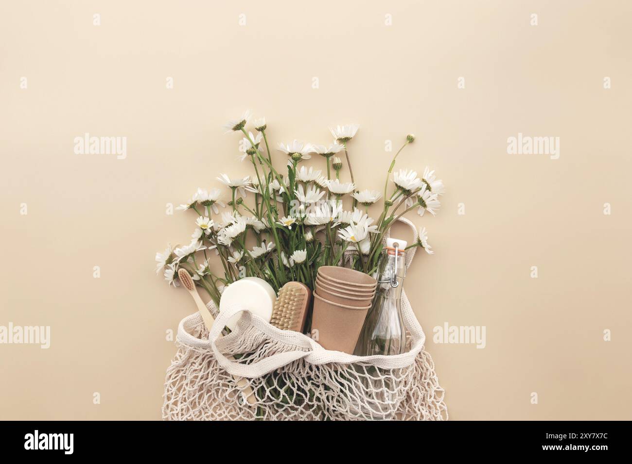 Eco friendly concetto estivo su sfondo beige con borsa eco shopping, fiori camomilla bianco, accessori da bagno, bottiglia di vetro d'acqua, sapone, dentifricio Foto Stock