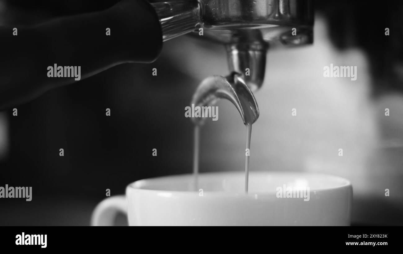 Primo piano dell'americano che viene versato dalla macchina per il caffè in una tazza. Caffè professionale per la preparazione di caffè nero. Macchina espresso professionale Foto Stock