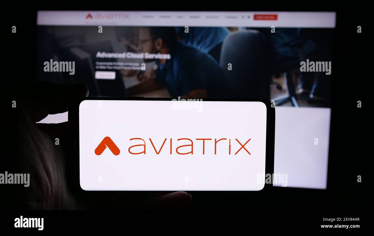 Persona che detiene un cellulare con il logo della società statunitense di cloud networking Aviatrix Systems Inc. Di fronte alla pagina Web aziendale. Mettere a fuoco il display del telefono. Foto Stock