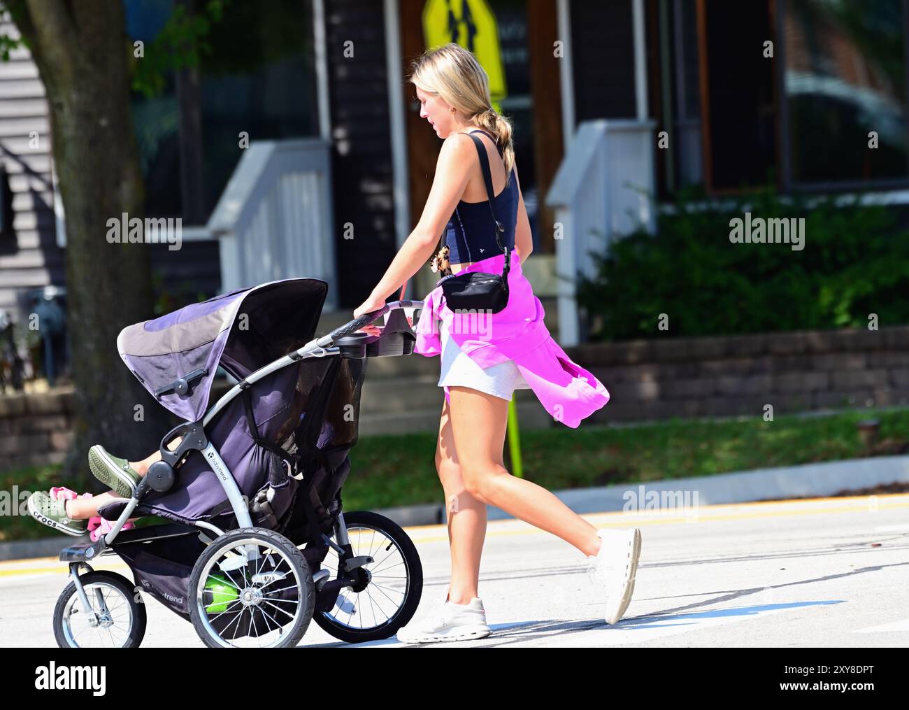 Winfield, Illinois, Stati Uniti. Una giovane donna spinge un passeggino mentre cammina lungo un marciapiede in un sobborgo di Chicago. Foto Stock