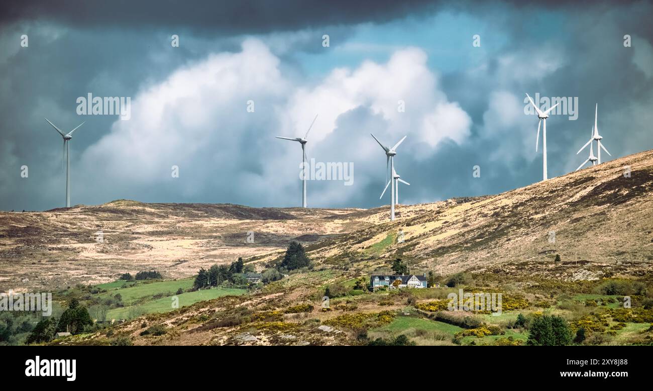 Poche turbine eoliche sono alte su una collina, catturando l'energia del vento sotto un cielo nuvoloso. Foto Stock