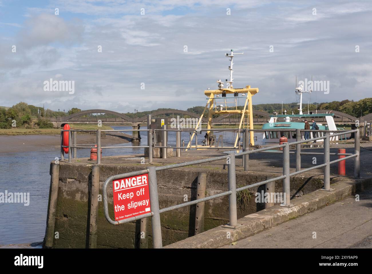 Porto di Kirkcudbright con un cartello di pericolo per tenere lontano lo scalo. Barche da pesca e Kirkcudbright o Dee Bridge Behind, agosto 2024, Scozia. Foto Stock