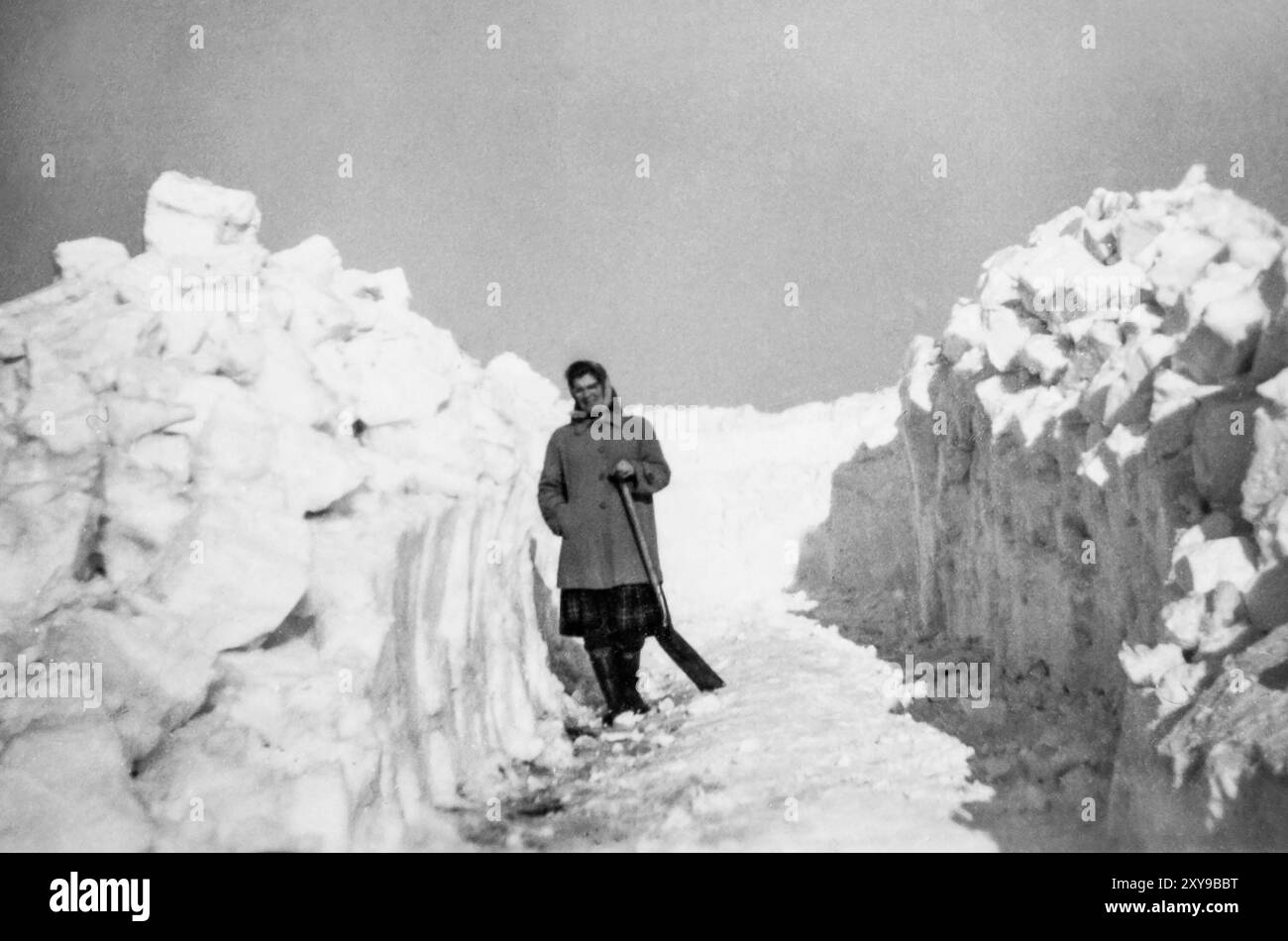 Inverno 1963: Irene Rutherford sgomberando un sentiero attraverso una deriva di neve per accedere al garage di Dodburn vicino Hawick, Scottish Borders, Regno Unito, Foto Stock