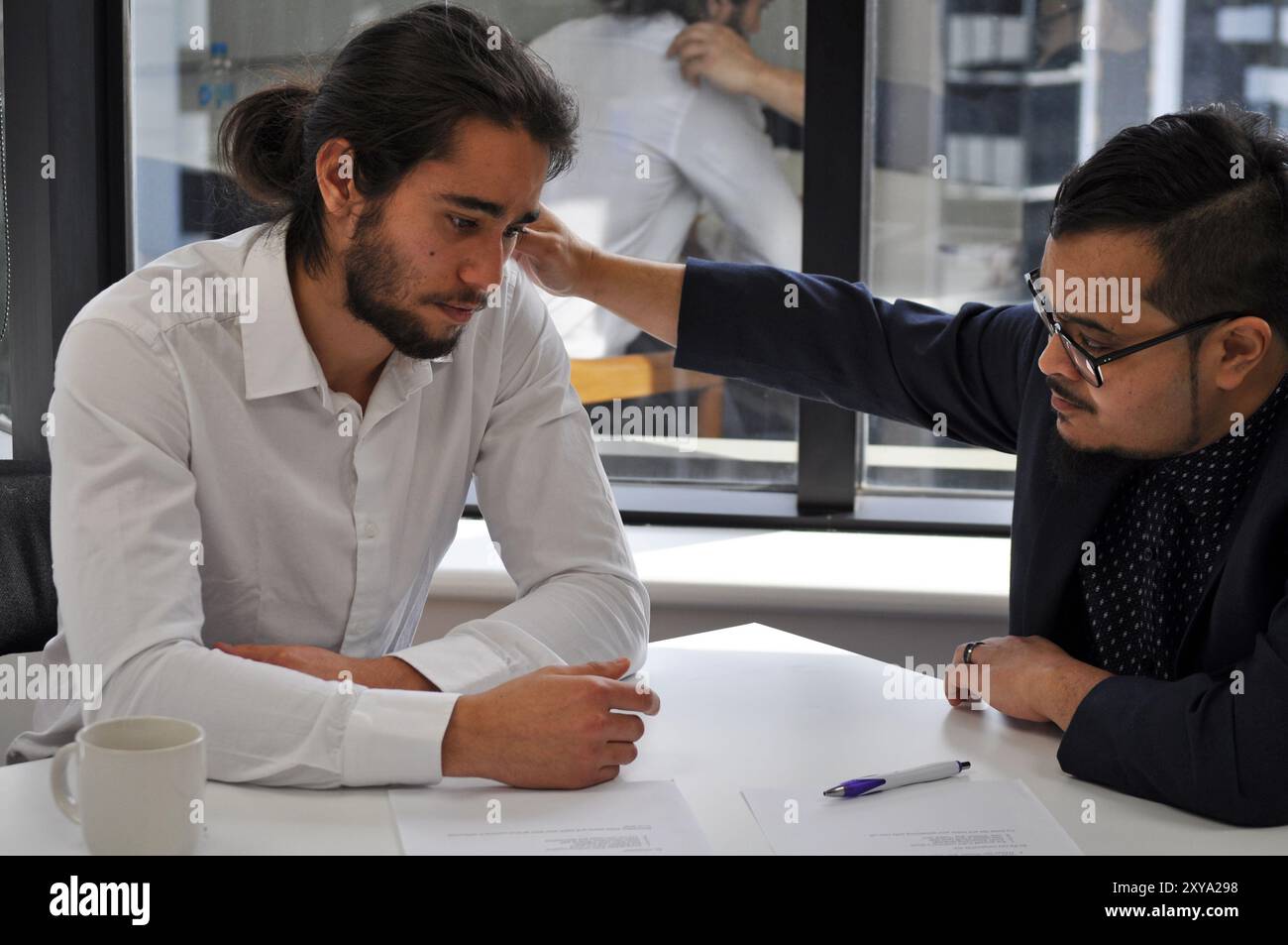 Due uomini in un ufficio con uno di loro che offre supporto Foto Stock