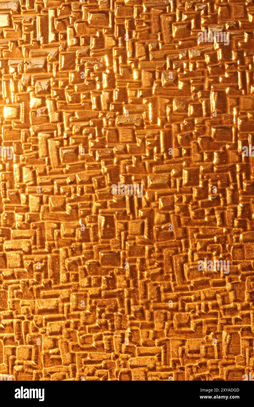 Un primo piano di vetro lucido che riflette le calde sfumature dorate della luce del tramonto. La trama astratta evidenzia l'interazione tra luce e superficie, creato Foto Stock